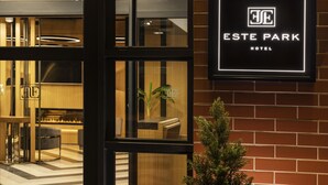 L’entrée d’un hôtel, avec un comptoir de réception, une petite plante et une enseigne indiquant « ESTE PARK HOTEL ».