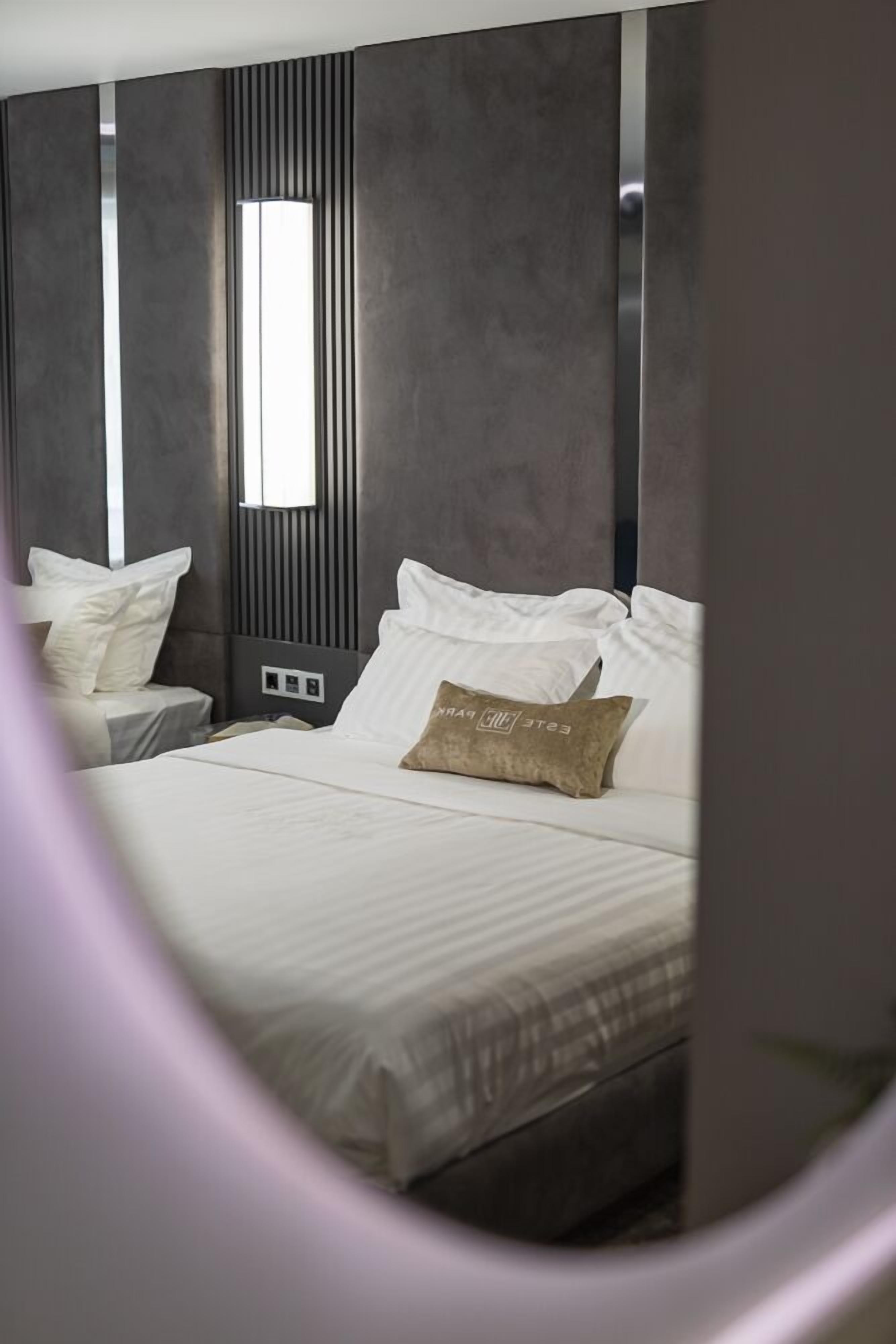 A modern hotel room with a large bed, two bedside tables, and a window.