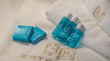 A white towel with embossed text reading "ESTE PARK" and three blue bottles with white caps.