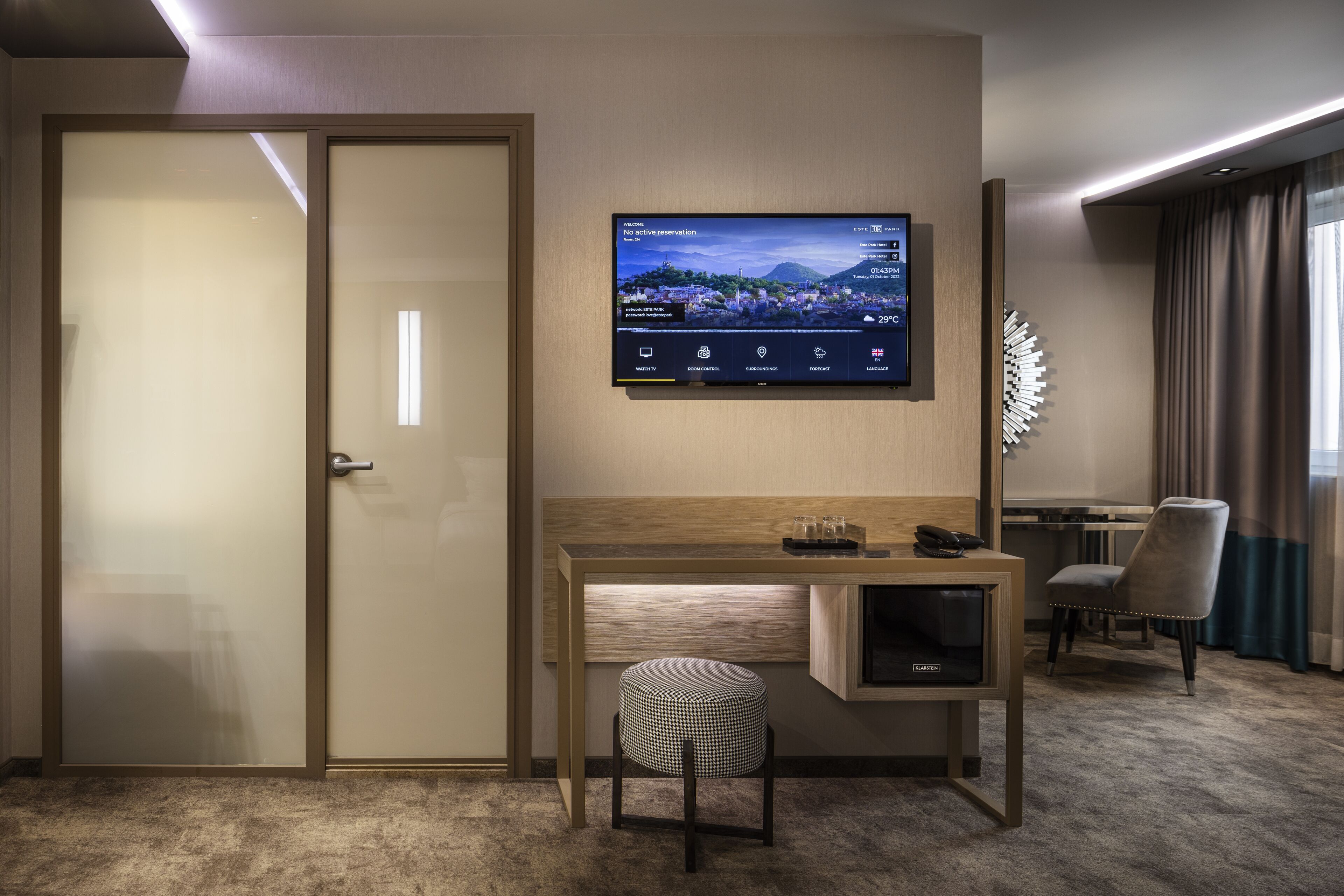 Ein Hotelzimmer mit Schreibtisch, Wandfernseher, Stuhl und Bett.