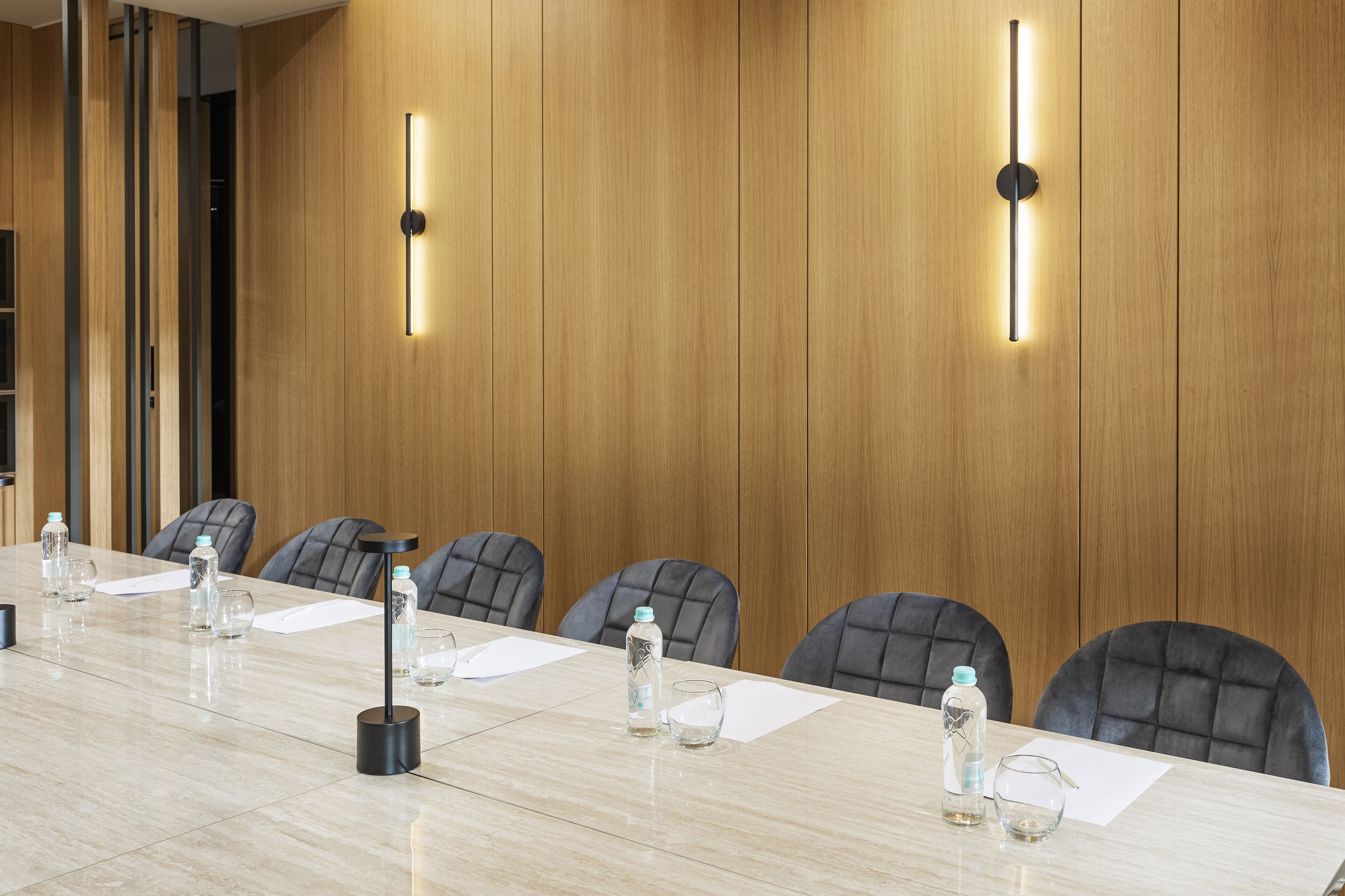 A conference room with a long table, chairs, water bottles, and papers.