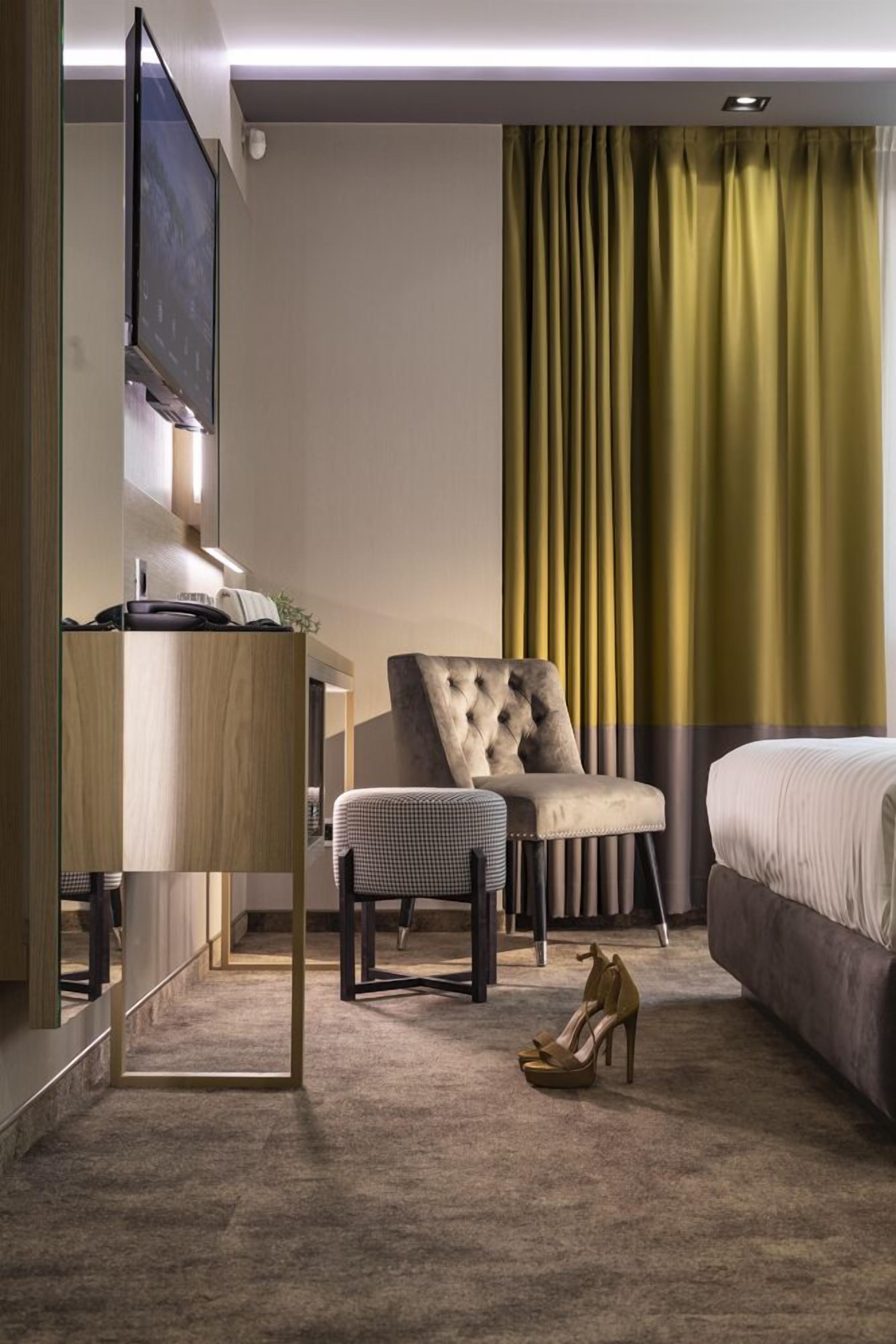 Une chambre d’hôtel avec un lit, un bureau, une chaise et un téléviseur.