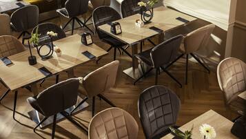 A hotel dining area with multiple tables and chairs, arranged in a spacious layout.