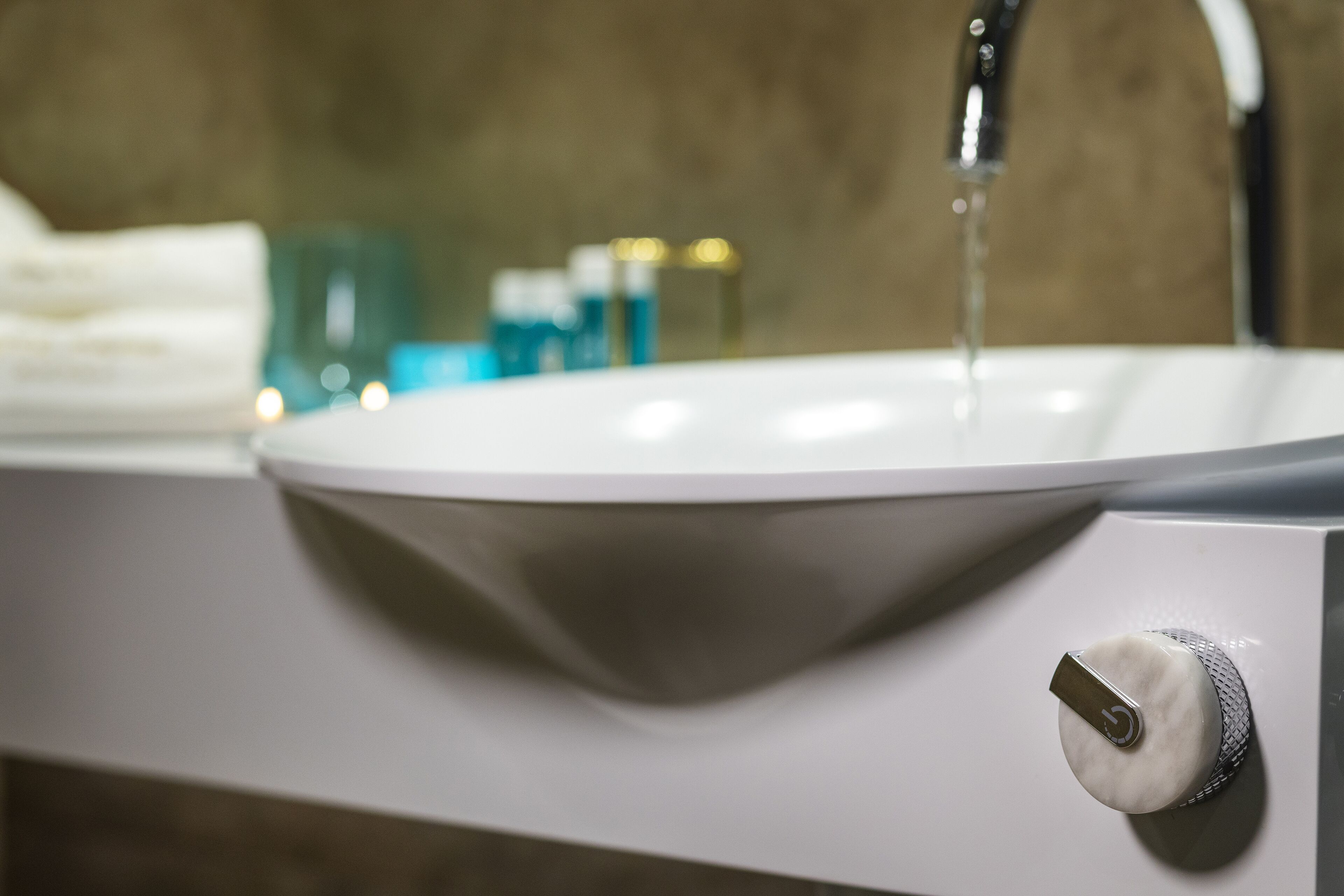 Un lavabo de salle de bain avec un robinet, un distributeur de savon et un porte-serviettes en arrière-plan.