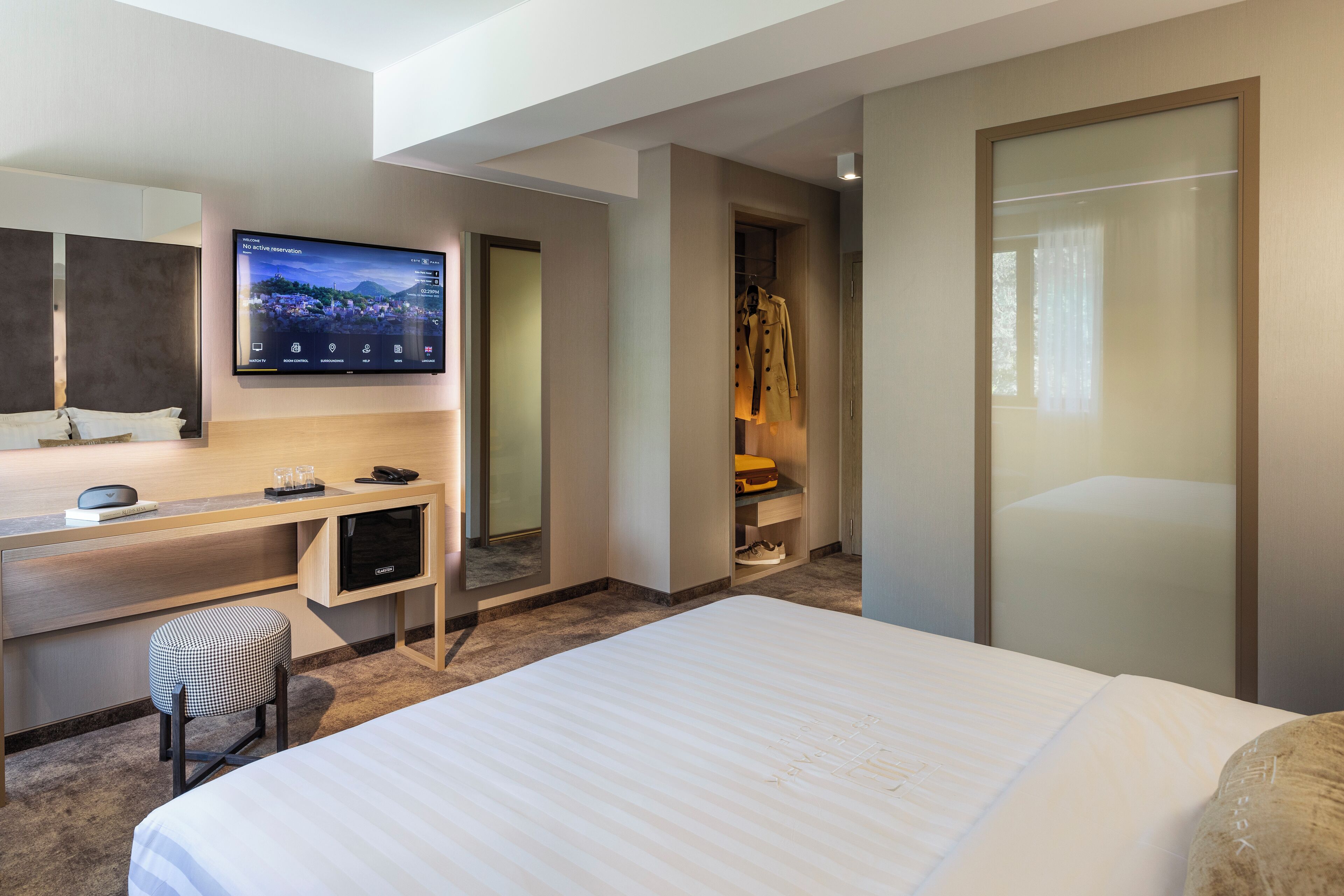 Habitación de hotel moderna con una cama grande, un escritorio con ordenador, un televisor de pantalla plana y un vestidor.