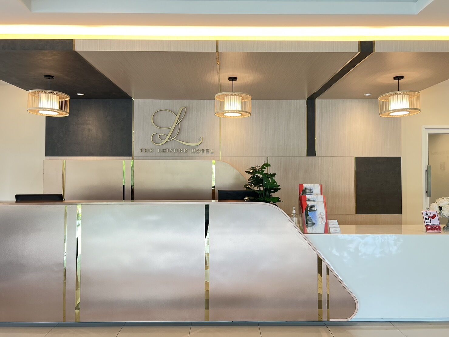 Un mostrador de recepción de hotel con diseño moderno, un logotipo sobre el mostrador y tres lámparas colgantes.