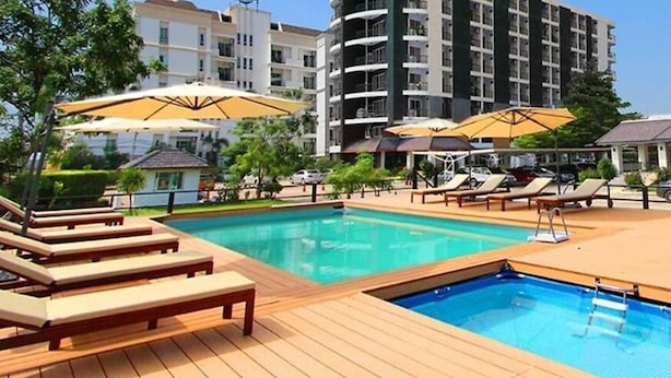 Une piscine entourée de bâtiments modernes, avec des chaises longues et des parasols.