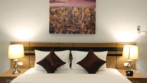 Une chambre d’hôtel avec vue sur la ville, un chevet en bois, deux lampes de chevet et deux oreillers marron.