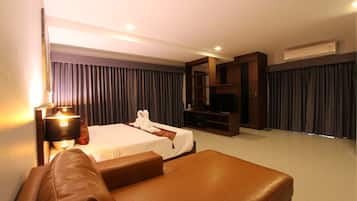 A hotel room with a bed, a sofa, a TV, and a minibar.