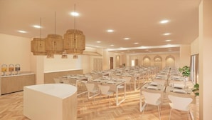 Une salle de conférence spacieuse, dotée de plusieurs tables et chaises, un espace d’accueil avec un comptoir et un lustre moderne.