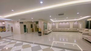 Un hall d’entrée spacieux, doté d’un sol à carreaux, de plusieurs espaces aménagés pour s’asseoir et d’un comptoir d’accueil.