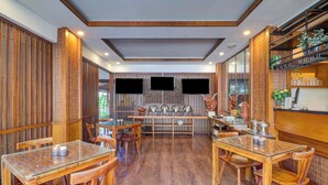A restaurant with wooden furniture, a central dining area, and a counter with shelves. - Palette near Legian Beach formerly Argya Santi Suites And Villas (Legian)