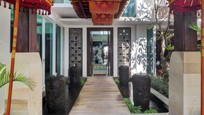 A pathway leading to a room with a decorative ceiling, a statue, and a water feature. - Palette near Legian Beach formerly Argya Santi Suites And Villas (Legian)