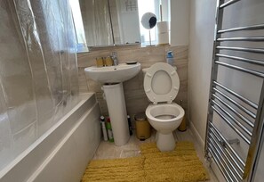 A bathroom with a bathtub, sink, toilet, and a window with a view. - Enjoy Lovely 4 bed Apartment With Garden (London)