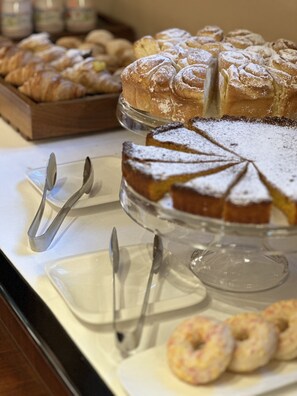 Una mesa de bufé con varios pasteles y una tarta sobre un soporte de vidrio.