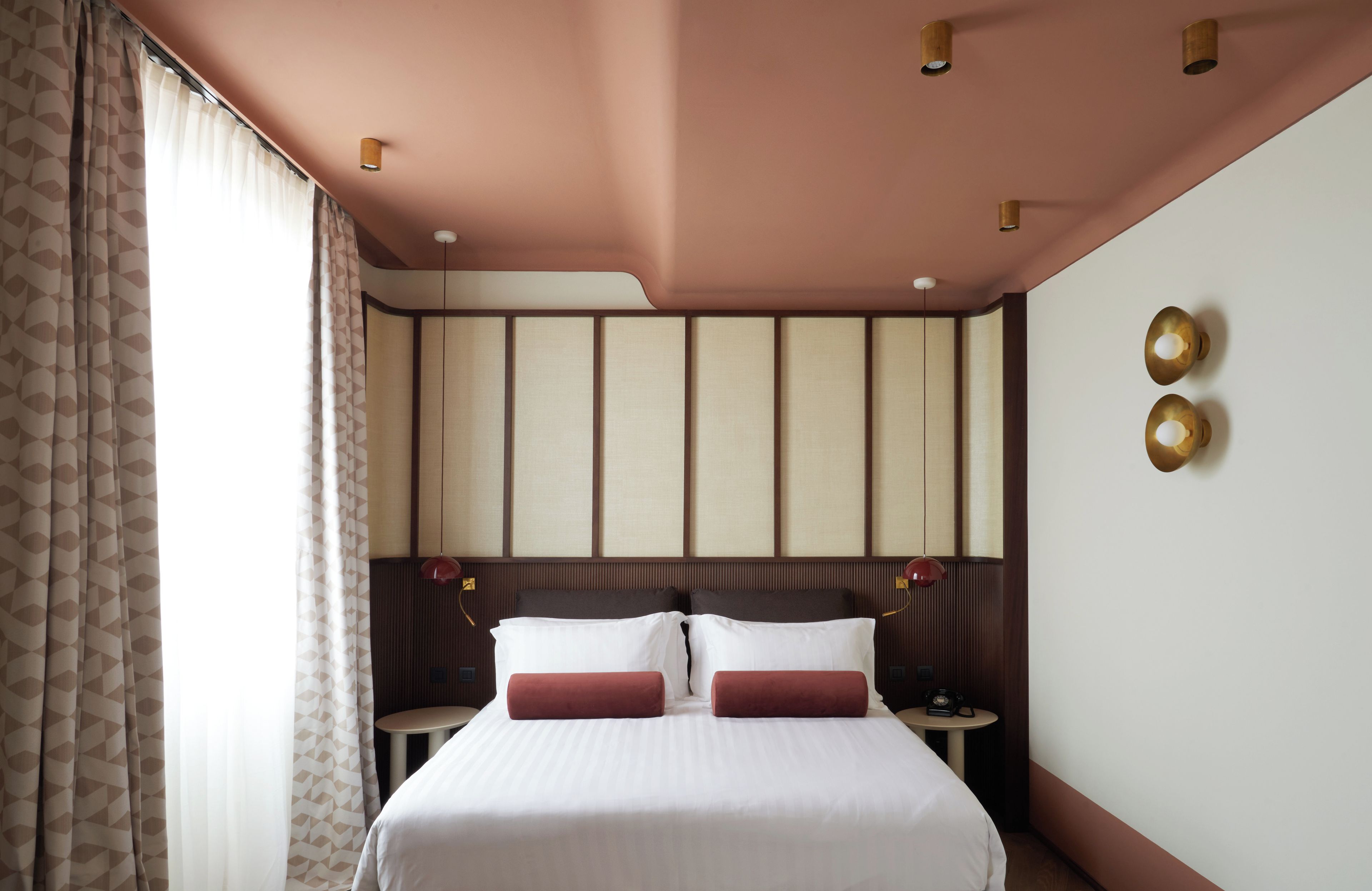 Ein Hotelzimmer mit einem Bett, Nachttischen und einer Wand mit dekorativen Paneelen.