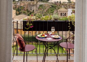 A balcony with two chairs, a table, and a hanging plant. The balcony overlooks a historic cityscape with ruins and buildings. - Palazzo Velabro, a Member of Design Hotels (Rome)