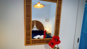 A room with a large mirror, a bed with blue bedding, a small table with a lamp, and a vase with red flowers. - Seaside Villa with private garden (Bonifati)