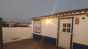 A building with two barred doors and a small window, surrounded by a white fence.
