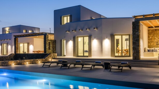 Ein modernes Gebäude mit Pool, Sitzgelegenheiten im Freien und Steindetails.