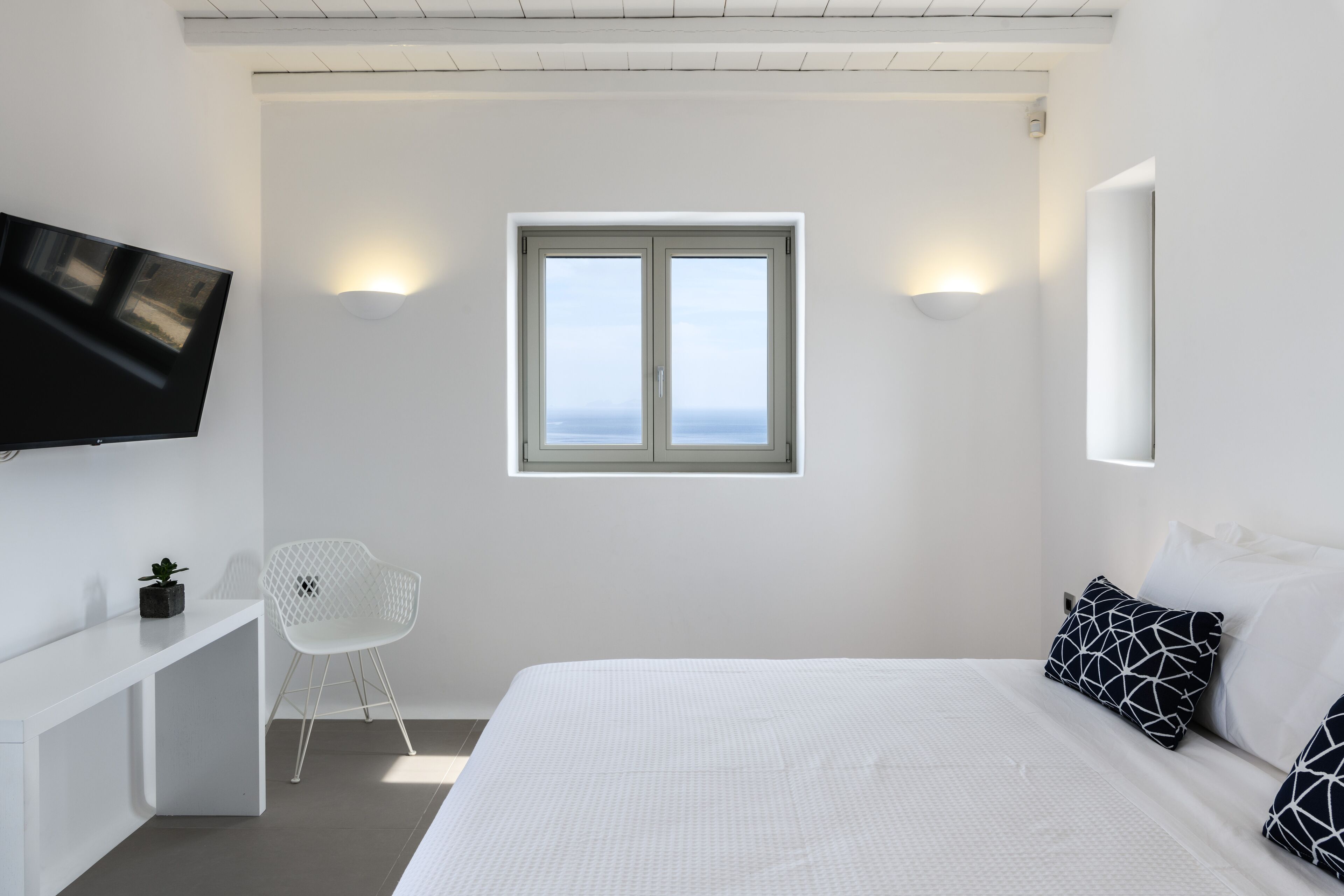 Habitació d'hotel moderna amb un llit, escriptori, cadira, televisió i finestra amb vistes.