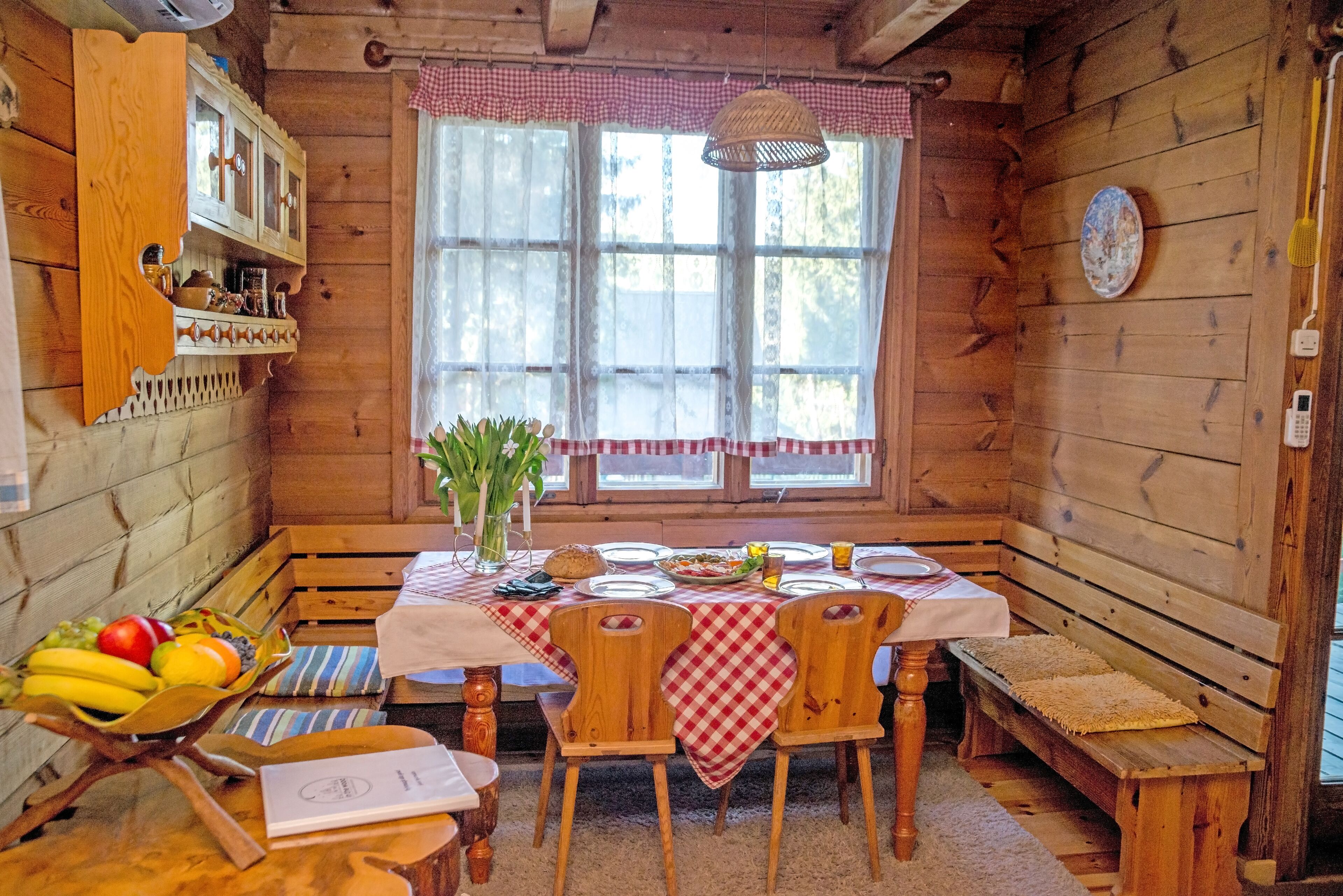 A wooden cabin interior with a dining table set for four, surrounded by wooden benches.