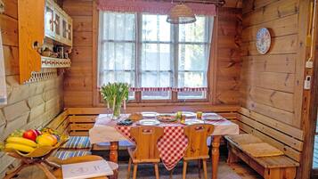 A wooden cabin interior with a dining table set for four, surrounded by wooden benches.