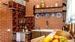Una cuina amb paret de maó, armaris de fusta, un rentaplat i un plat de fruita.
