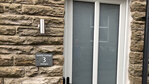 Un muro de piedra con una puerta blanca y un letrero que dice 'Quartz Cottage 3 Middlegate'.