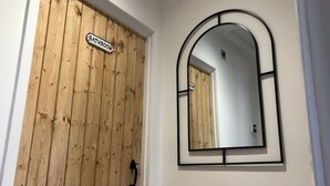 Una puerta de madera con un cartel que dice 'Bathroom' y un espejo con marco negro.