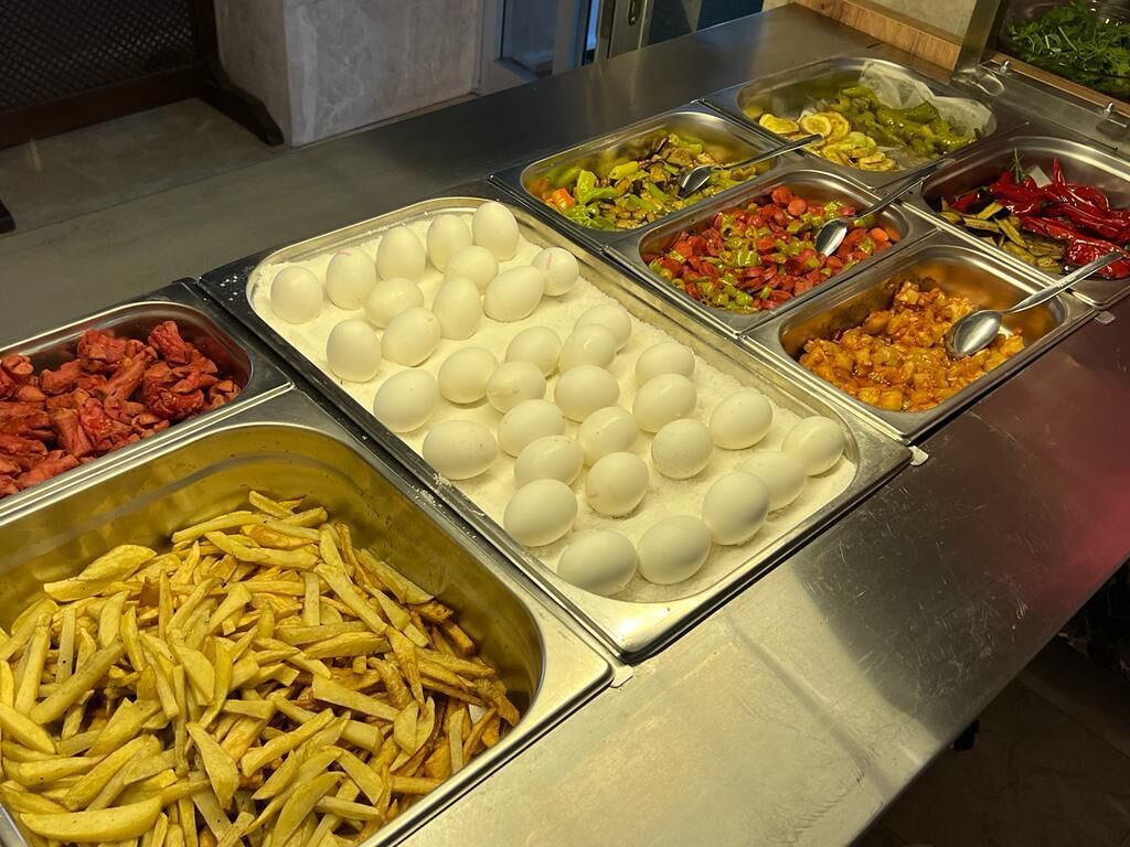 A buffet with various food items including eggs, French fries, and mixed vegetables.