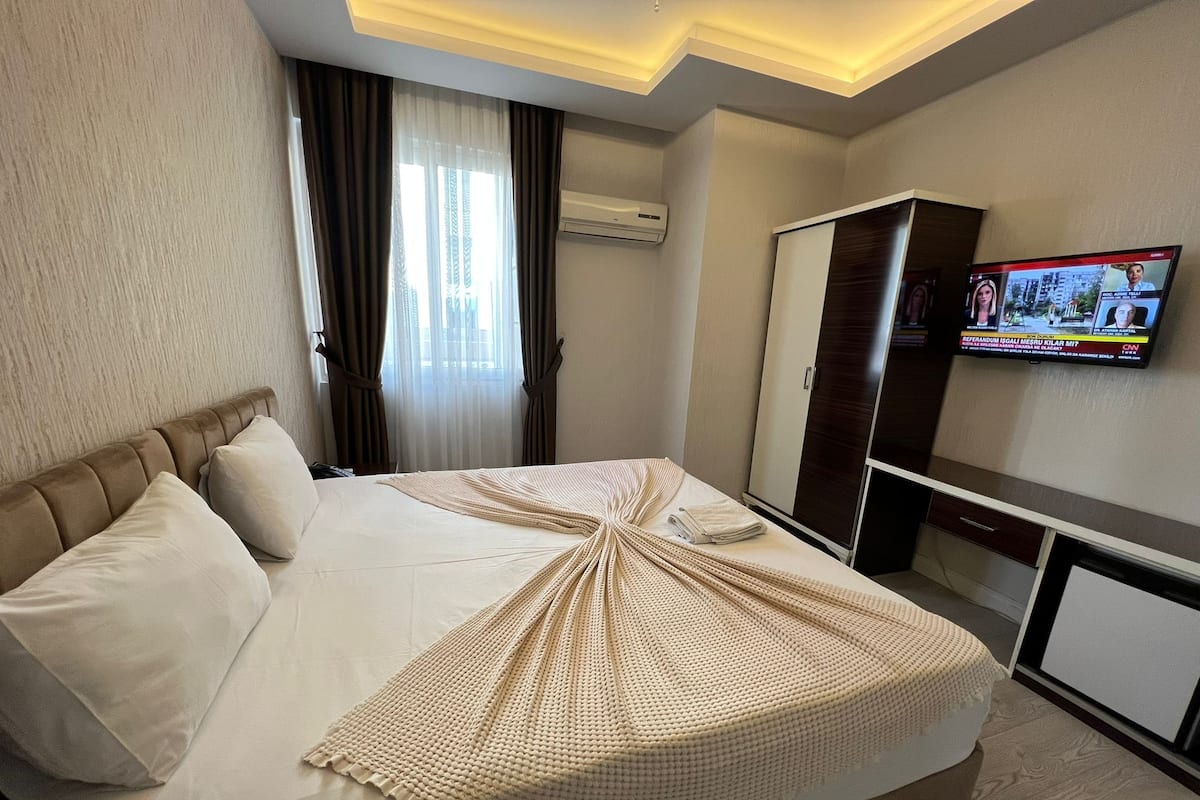 Ein Hotelzimmer mit Bett, Fernseher, Kleiderschrank und Klimaanlage.
