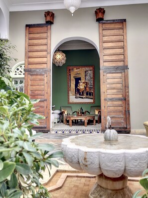 Una stanza con un'ampia porta in legno, una fontana circolare in marmo e un quadro appeso al muro.