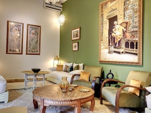 Un salon avec une table basse ronde en bois, un canapé et un grand tableau encadré accroché au mur.