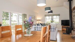 A spacious living room with a wooden dining table, a sofa set, and a television. - Bonnach (Muir of Ord)