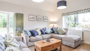 A cozy living room with a sectional sofa, a coffee table, and two pendant lights. - Bonnach (Muir of Ord)