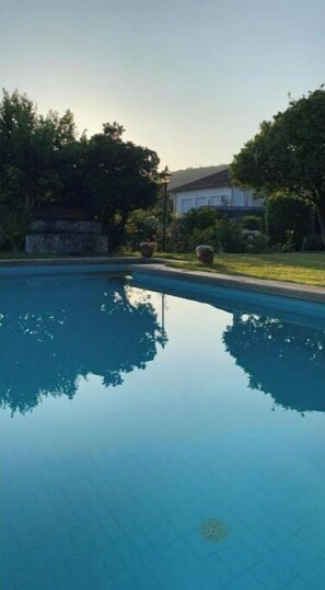 A swimming pool with clear water, surrounded by trees and a building in the background. - Casa Tabagon, a charming house with a pool. (San Juan de Tabagón (O Rosal, Pontevedra))