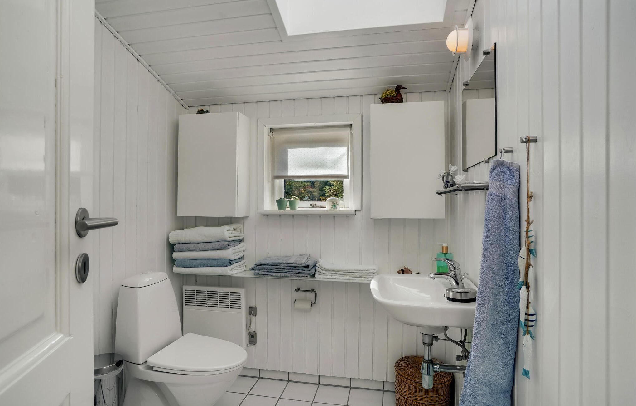 A compact bathroom with a toilet, sink, and window.