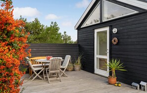 A wooden deck with a table and chairs, a potted plant, and a small house model. - 3 bedroom nice home in Ulfborg (Ulfborg)