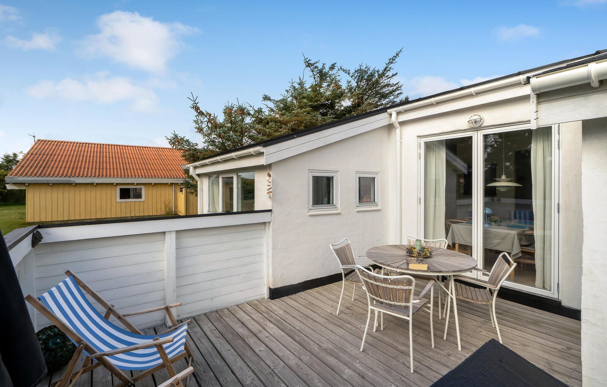 Un espace extérieur abrité, doté d’une table et de chaises, d’une terrasse et offrant une vue sur un bâtiment voisin.