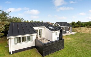 A modern house with a sloped roof, a patio with outdoor furniture, and a small deck. - 3 bedroom nice home in Ulfborg (Ulfborg)