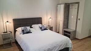 A modern bedroom with a large bed, two bedside tables with lamps, a wardrobe, and a mirror. - LA FACTORY by LNA (Porrentruy)