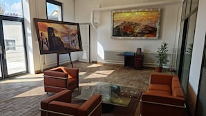 A modern living room with a large painting, leather sofas, a glass coffee table, and a view of the outside. - LA FACTORY by LNA (Porrentruy)