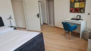 Ein Hotelzimmer mit Bett, Schreibtisch, Stuhl, Heizkörper und einem Wandbild.