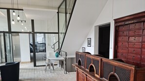 A modern interior with a wooden cabinet, a white table with a vase, and a glass door leading outside. - LA FACTORY by LNA (Porrentruy)