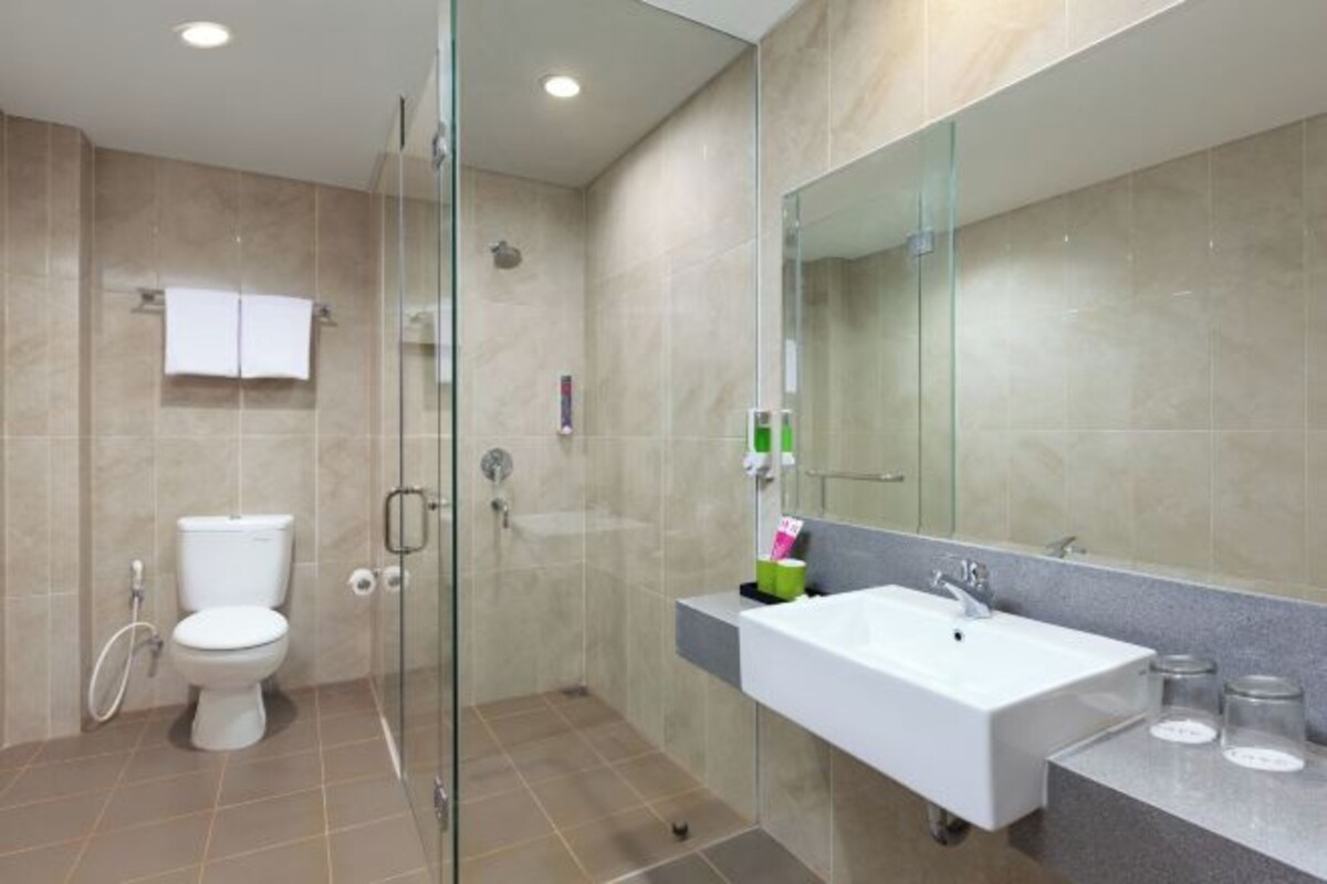 Un baño moderno con cabina de ducha de vidrio, un lavabo blanco y un espejo grande.