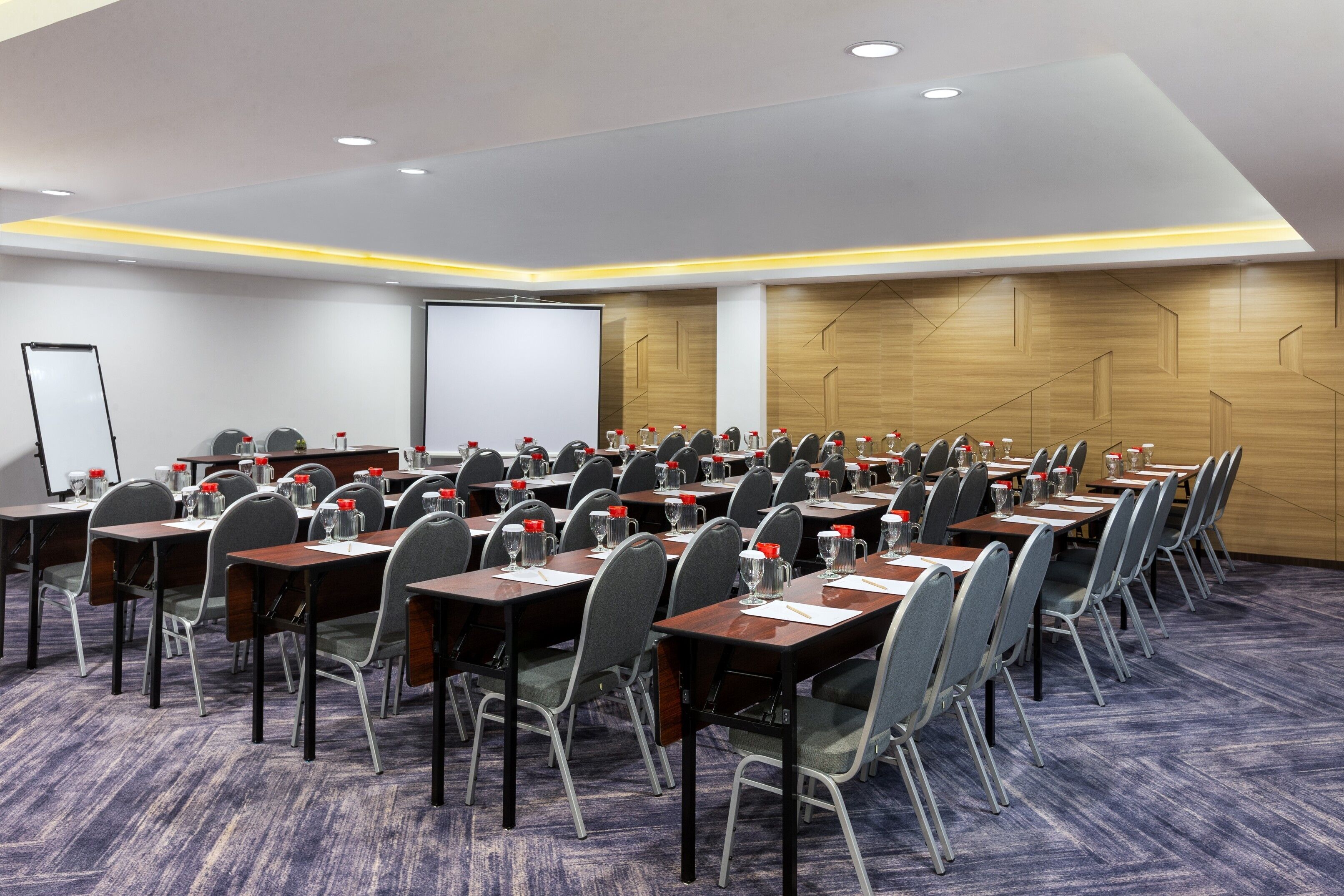A conference room with multiple tables and chairs, equipped with water bottles and glasses.