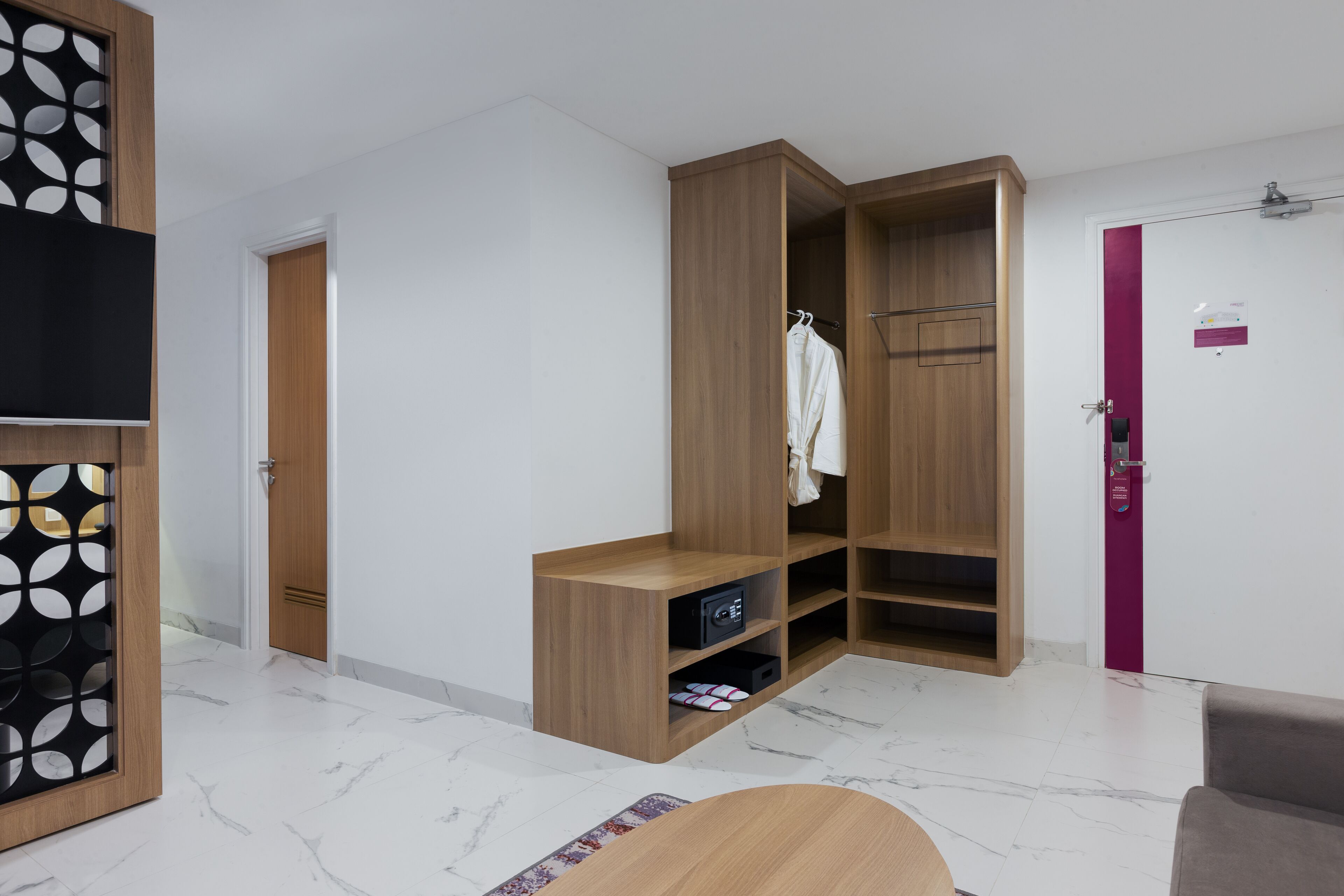 A modern room with a wooden wardrobe, a small seating area, and a television.