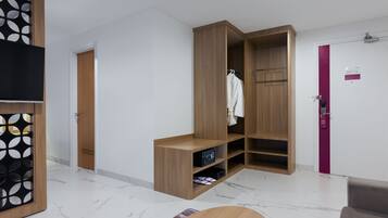 A modern room with a wooden wardrobe, a small seating area, and a television.