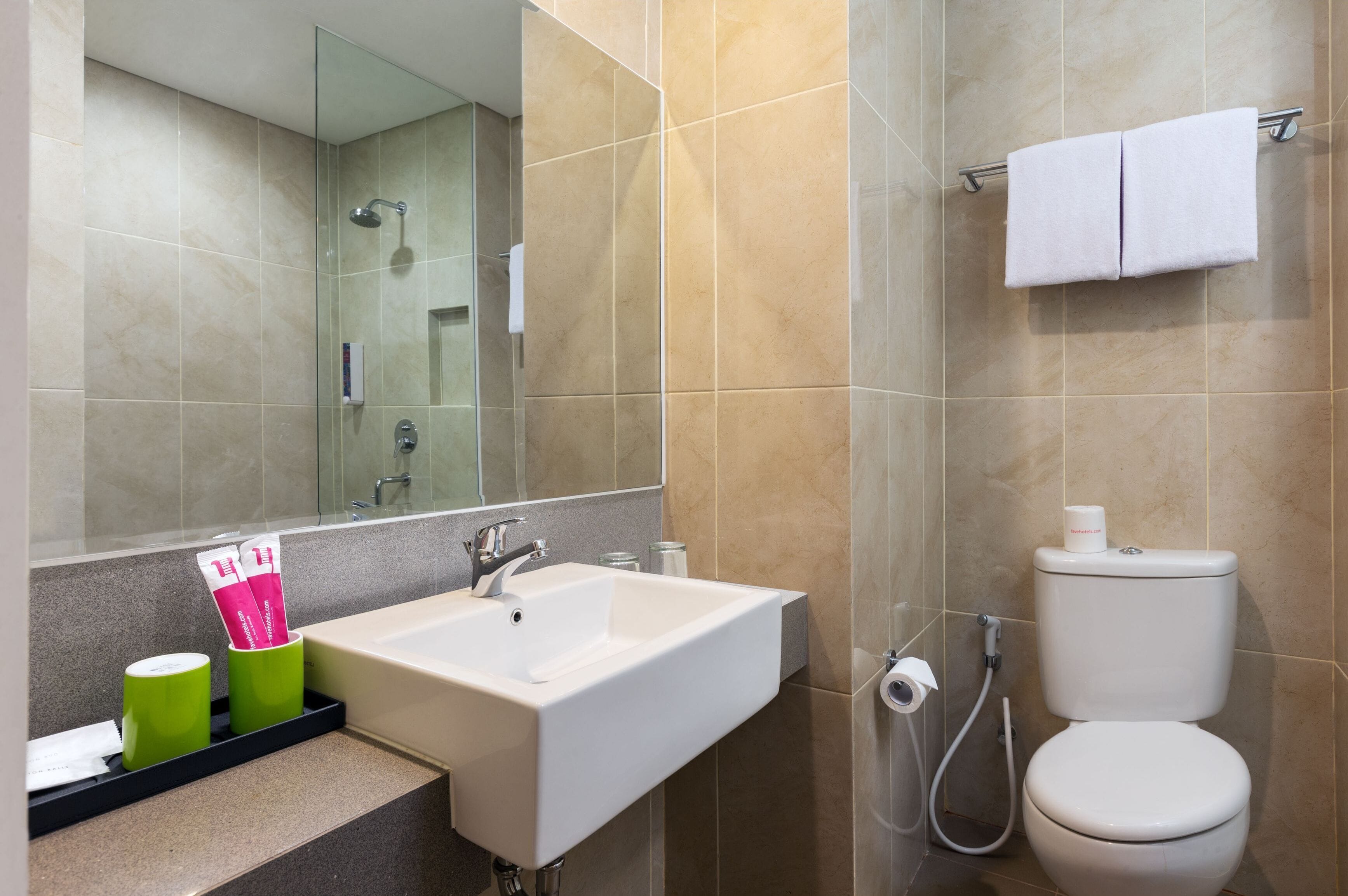 A modern bathroom with a white sink, a mirror, a toilet, and a shower.